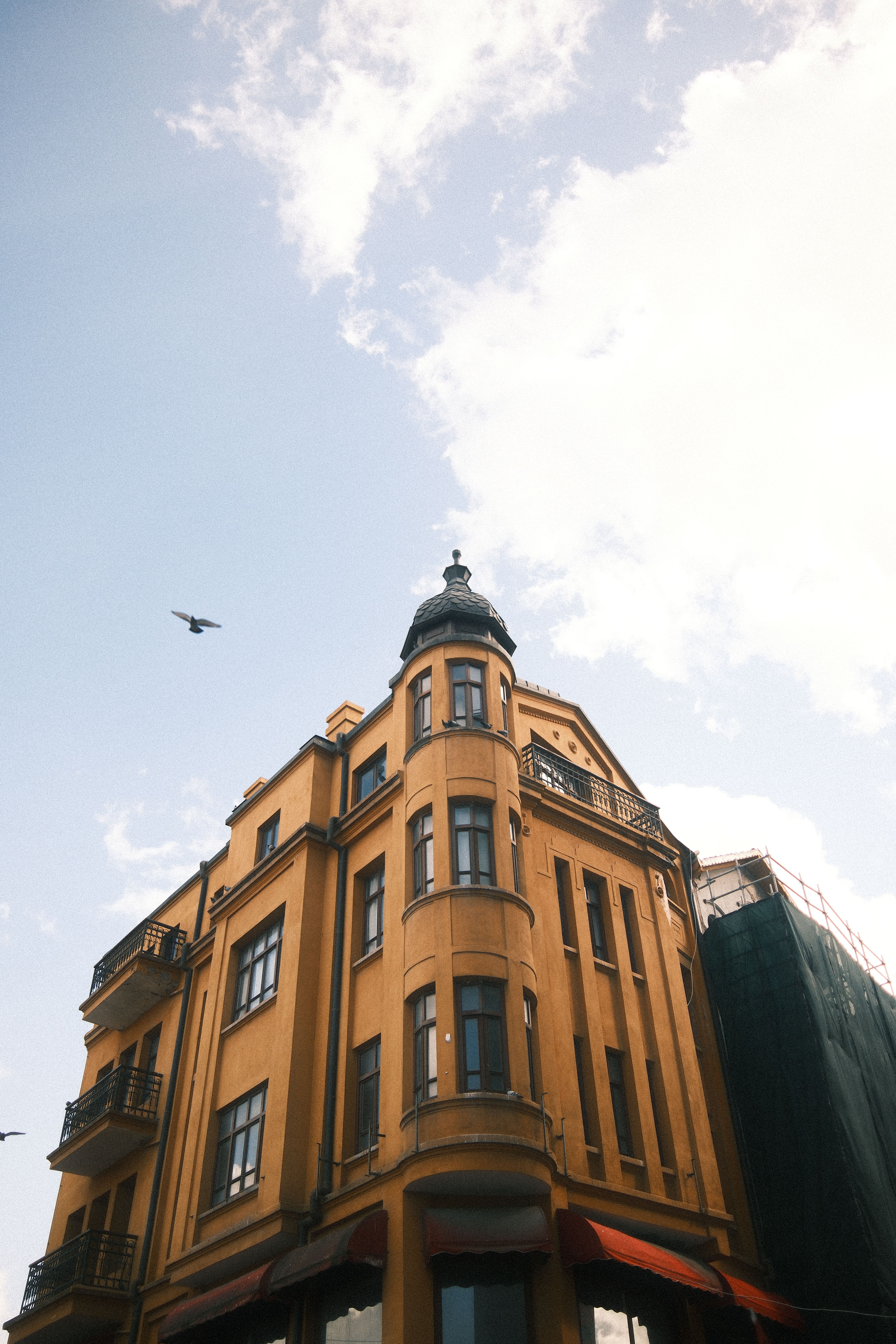Bezpłatne Elegancki żółty ceglany budynek z ozdobnymi detalami architektonicznymi na tle jasnego nieba. Zdjęcie z galerii