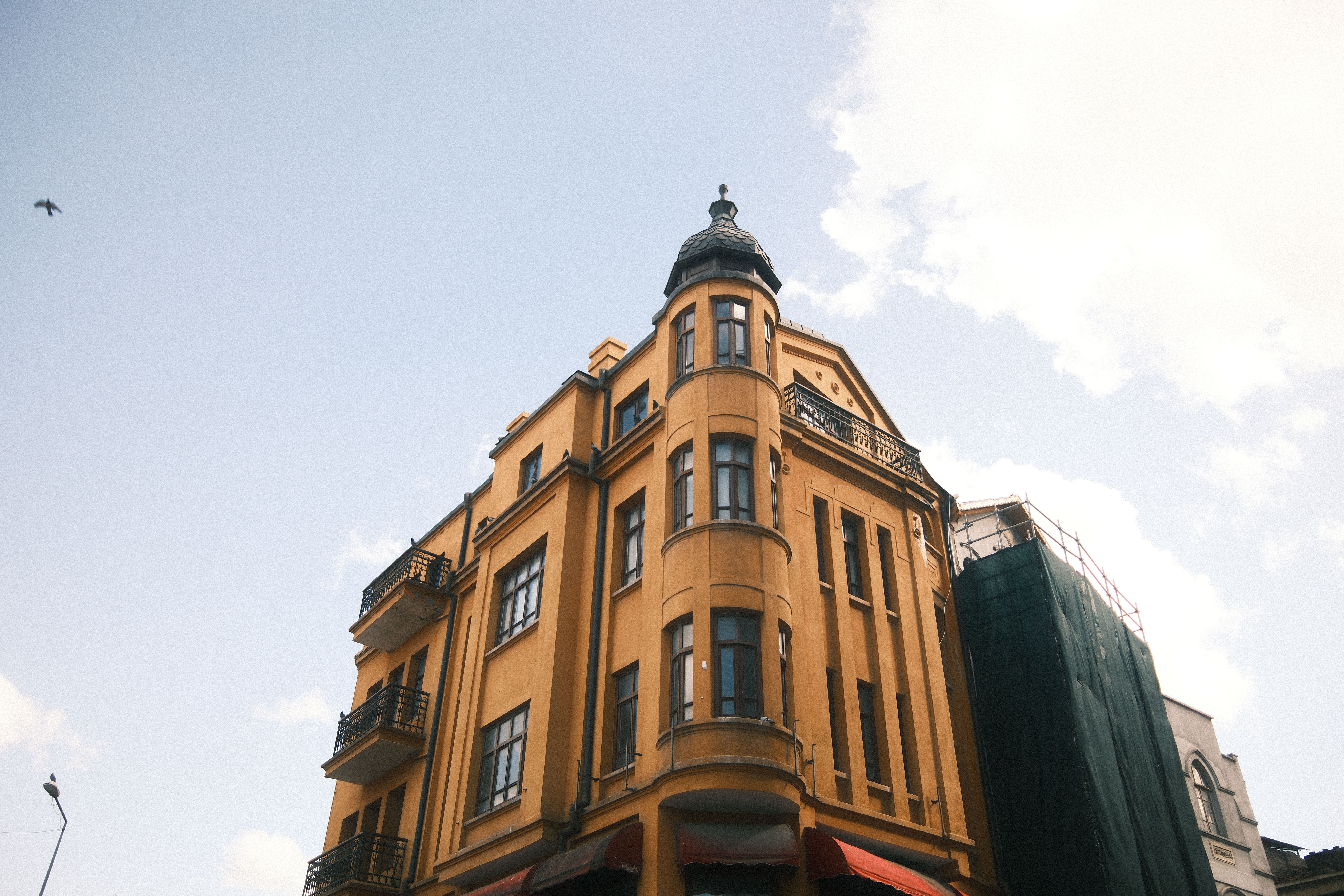 Bezpłatne Zabytkowy żółty budynek o wyjątkowej architekturze na tle jasnoniebieskiego nieba. Idealny do zdjęć o tematyce podróżniczej i architektonicznej. Zdjęcie z galerii