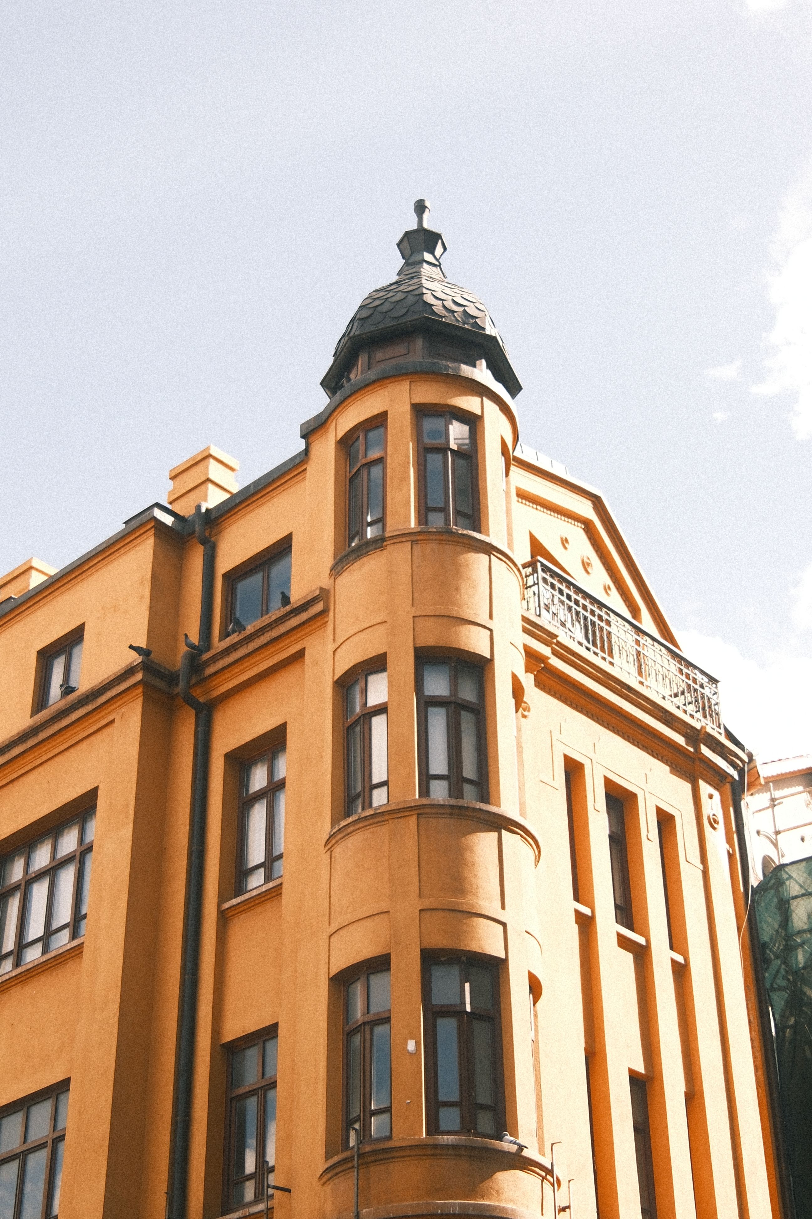Bezpłatne Zdjęcie zabytkowego europejskiego budynku z wyjątkową wieżą i jaskrawymi detalami architektonicznymi. Zdjęcie z galerii