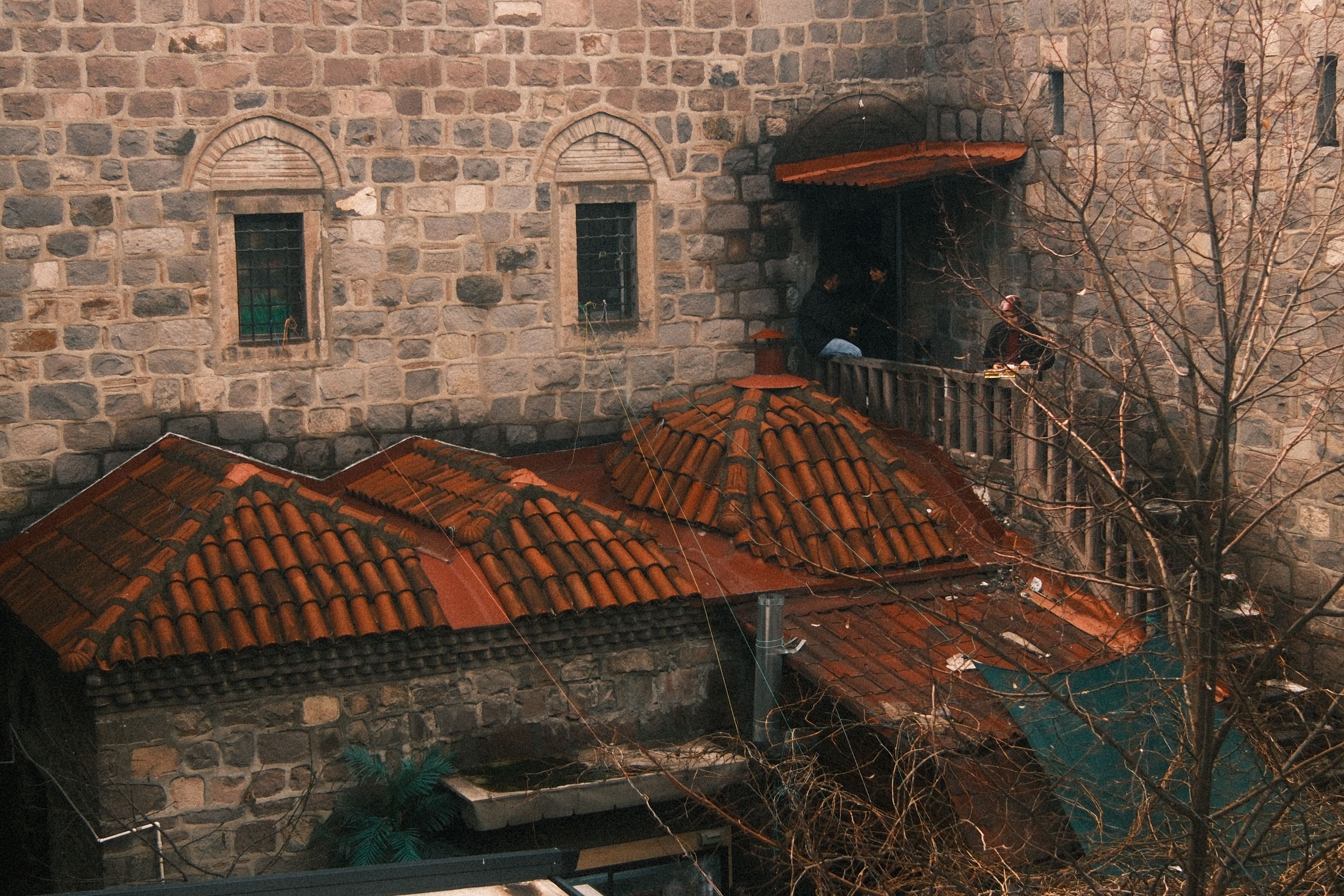 Bezpłatne Zabytkowa kamienna budowla z czerwonymi dachami krytymi dachówką i misternymi łukowymi oknami, odzwierciedlająca dziedzictwo architektoniczne. Zdjęcie z galerii