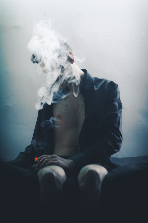 Free Artistic portrait of a person with smoke obscuring their face, creating a mysterious mood. Stock Photo