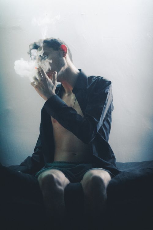 Free A contemplative young man smoking indoors, capturing a moody and dramatic ambiance. Stock Photo