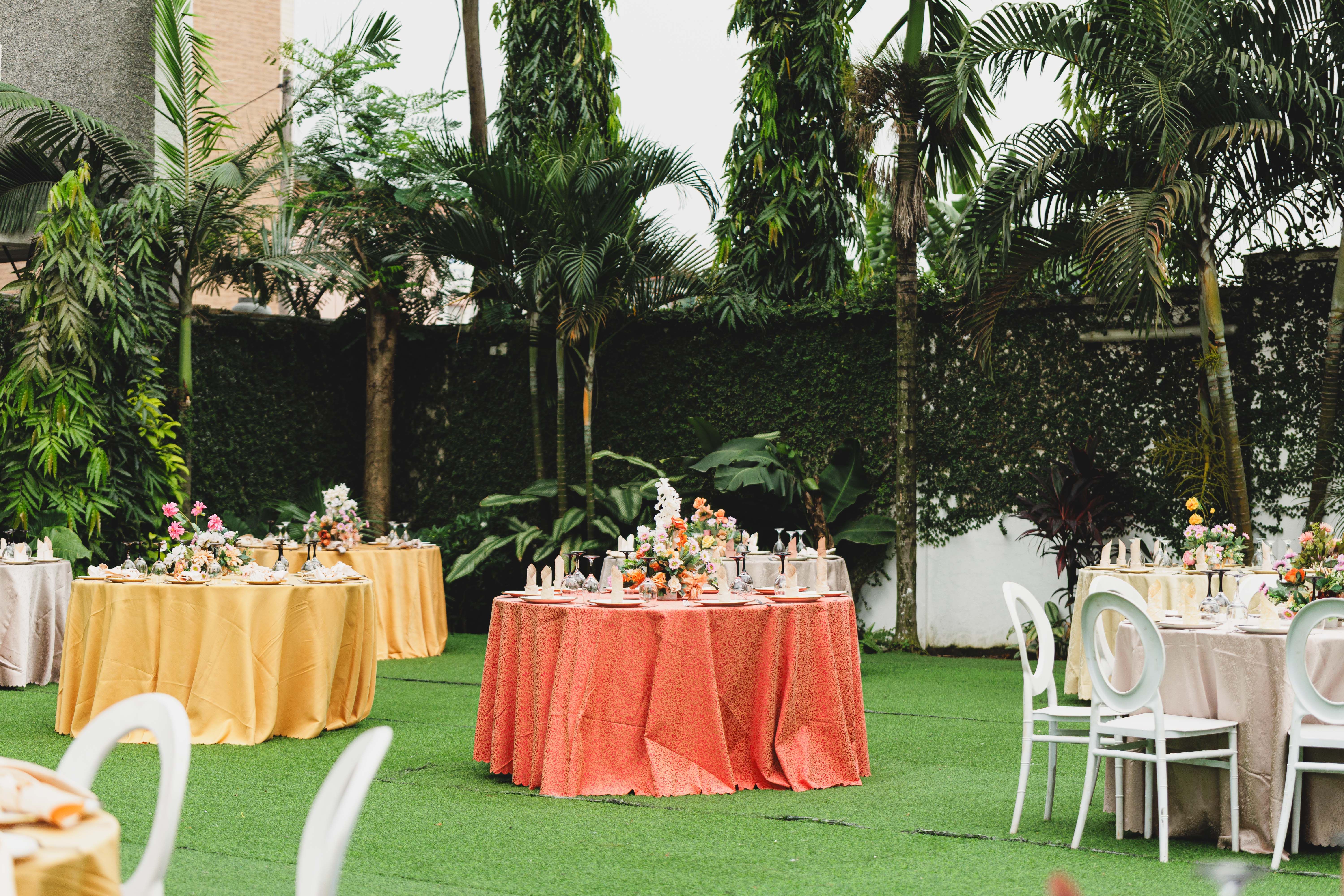 A beautifully arranged outdoor garden party with elegant floral decorations and colorful table settings.