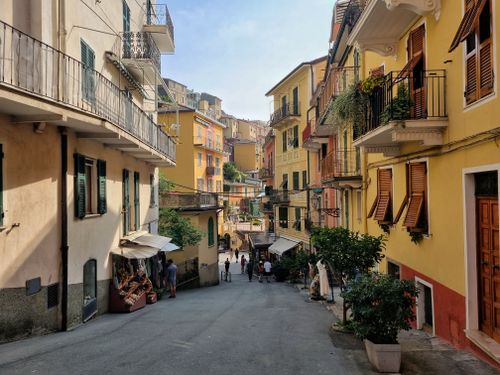 Free A picturesque street scene in Liguria, Italy, showcasing colorful Italian architecture under summer skies. Stock Photo