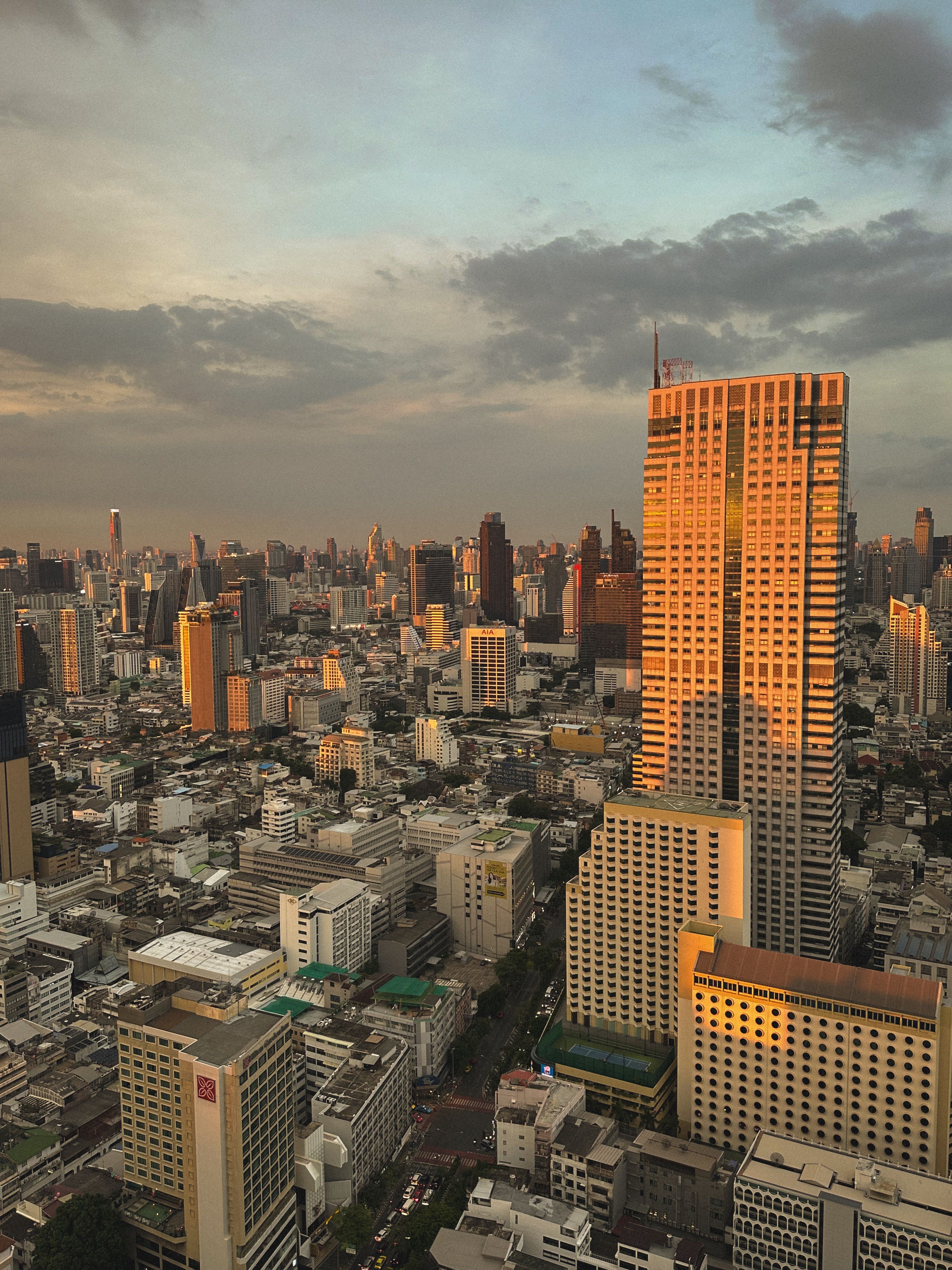 Aerial view of Bangkok's skyline at sunset, highlighting the golden-lit skyscrapers and urban landscape.