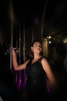 Portrait of a woman in a black dress surrounded by glowing light poles at night.