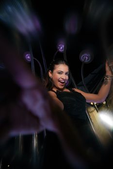 Smiling woman in black dress celebrating with energetic vibe at a night event.