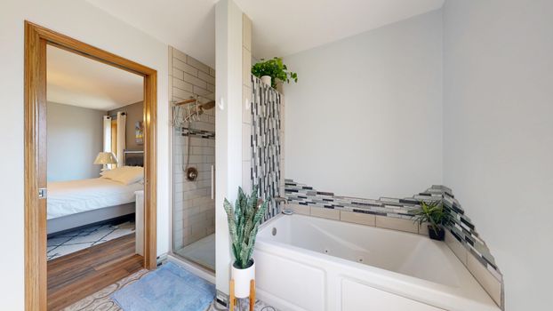 Spacious modern bathroom featuring a jacuzzi, shower, and plants enhancing the decor.