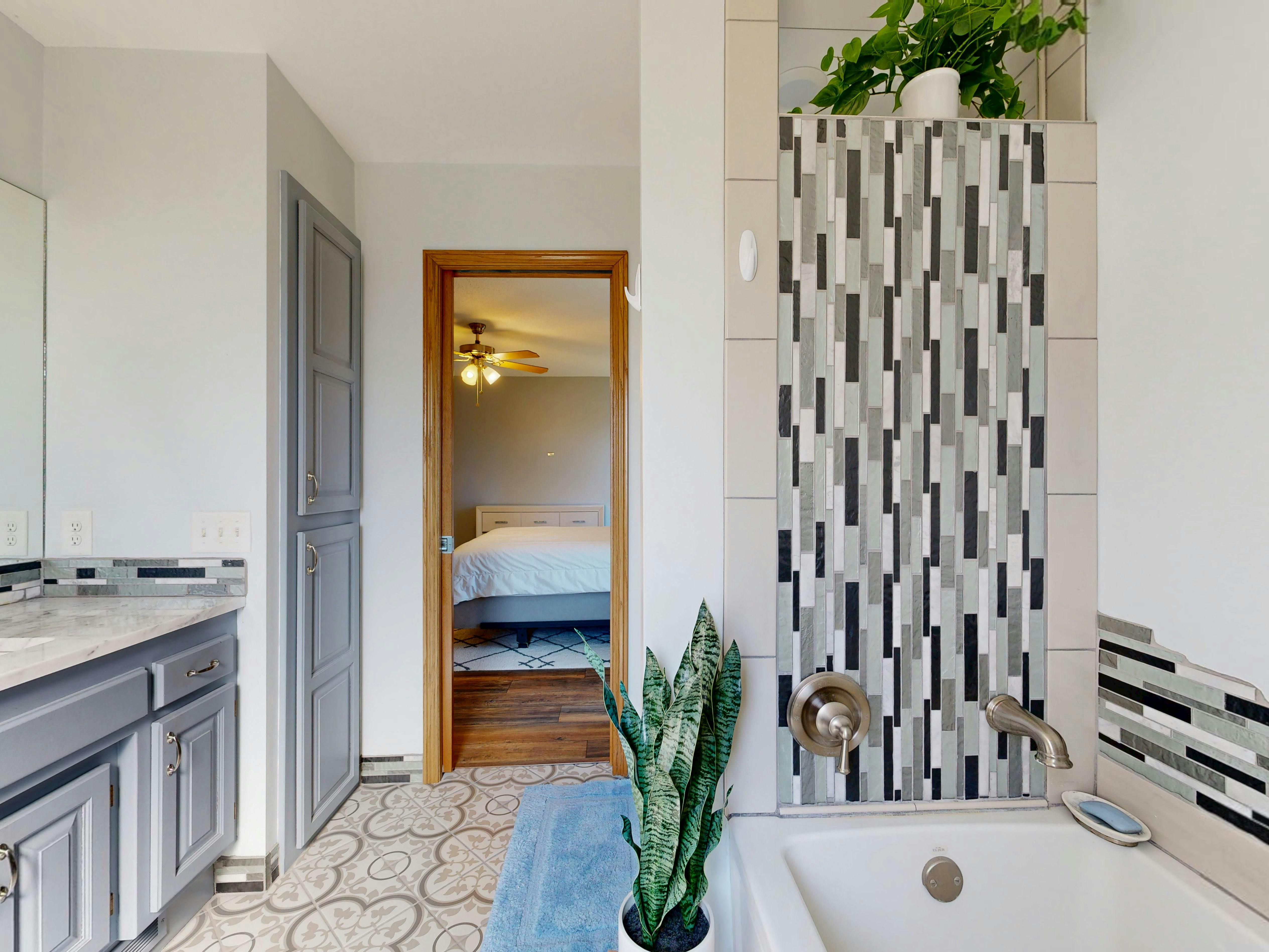 Stylish bathroom with tiled shower and view into a cozy bedroom.