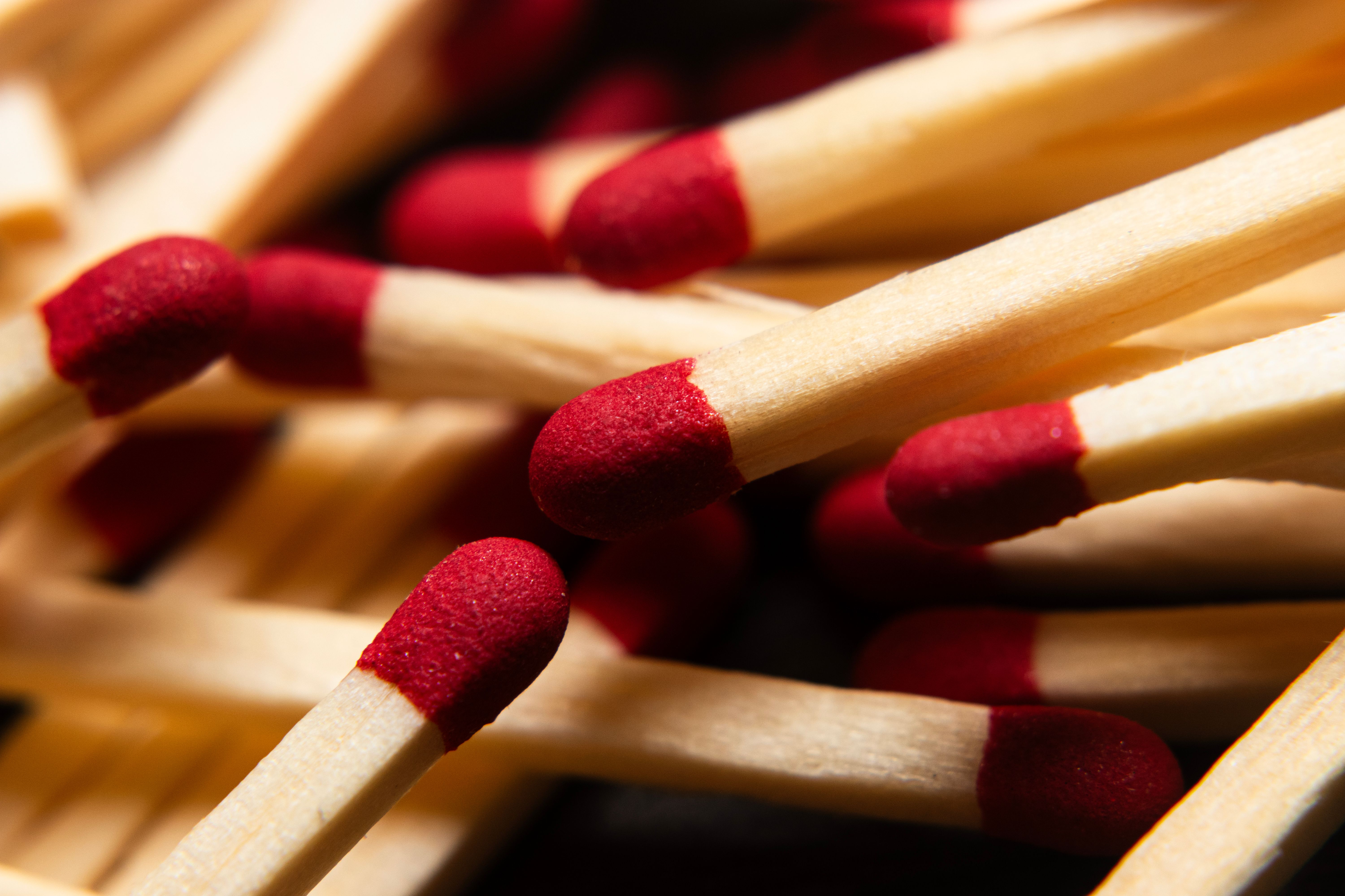 Macro image of red-tipped wooden matchsticks, ideal for fire starting concepts.