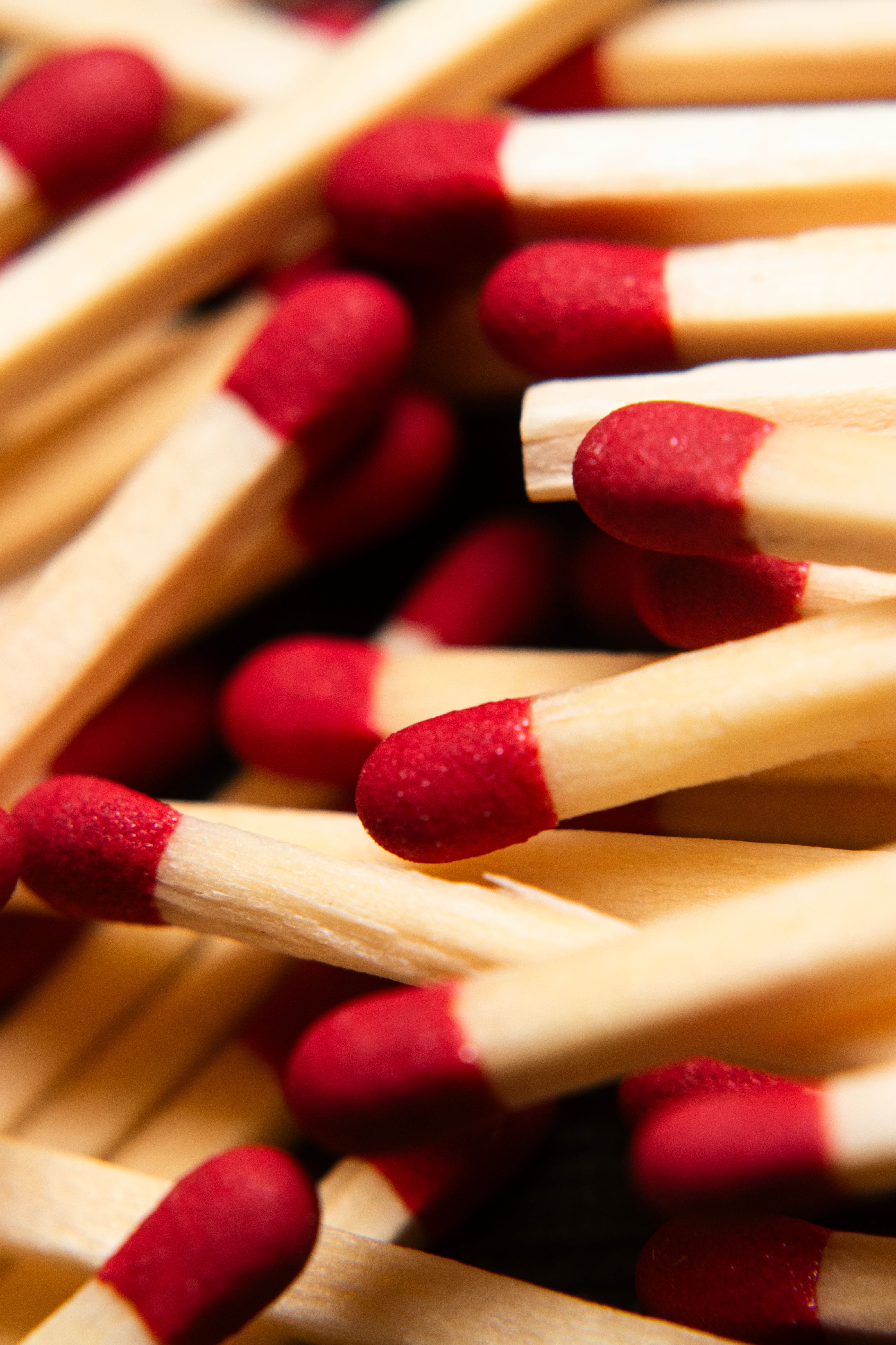A detailed close-up image of wooden matchsticks with red tips, highlighting their texture and pattern.