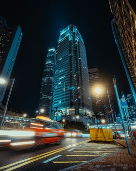 Dramatic nighttime cityscape featuring light trails and towering skyscrapers under a dark sky.