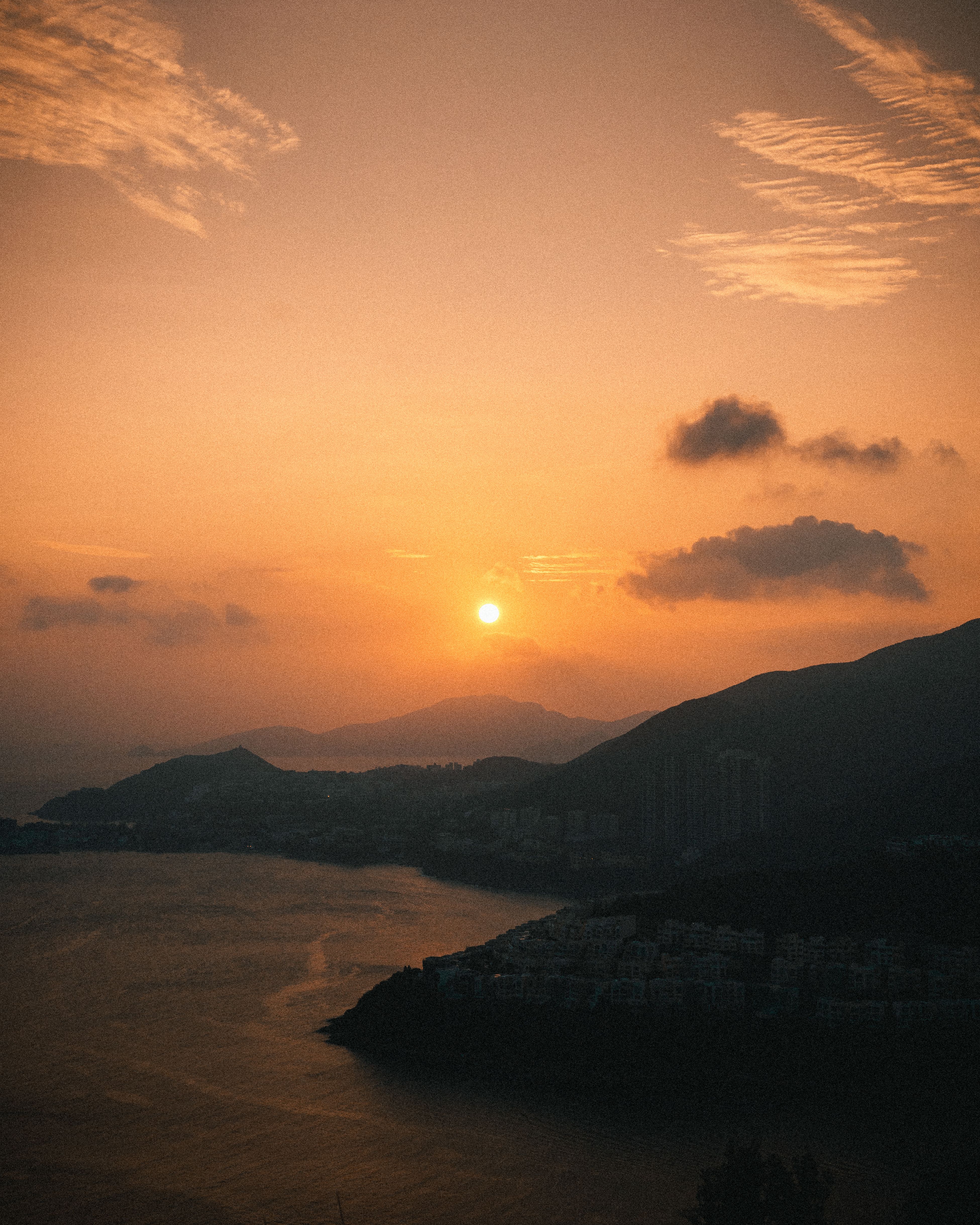 A breathtaking sunset view over a coastal town with silhouetted hills.