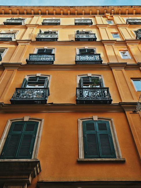 Elegant historical building facade with orange walls and green shutters in Europe.