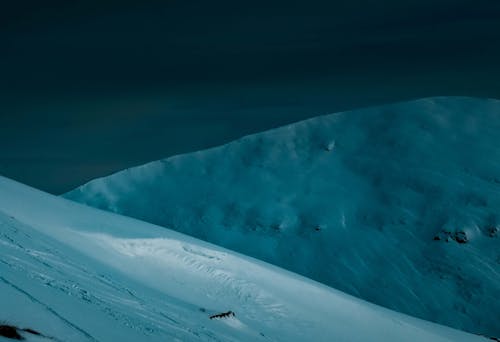 Picturesque scenery of mountain ridge covered with thick layer of snow against dark night sky