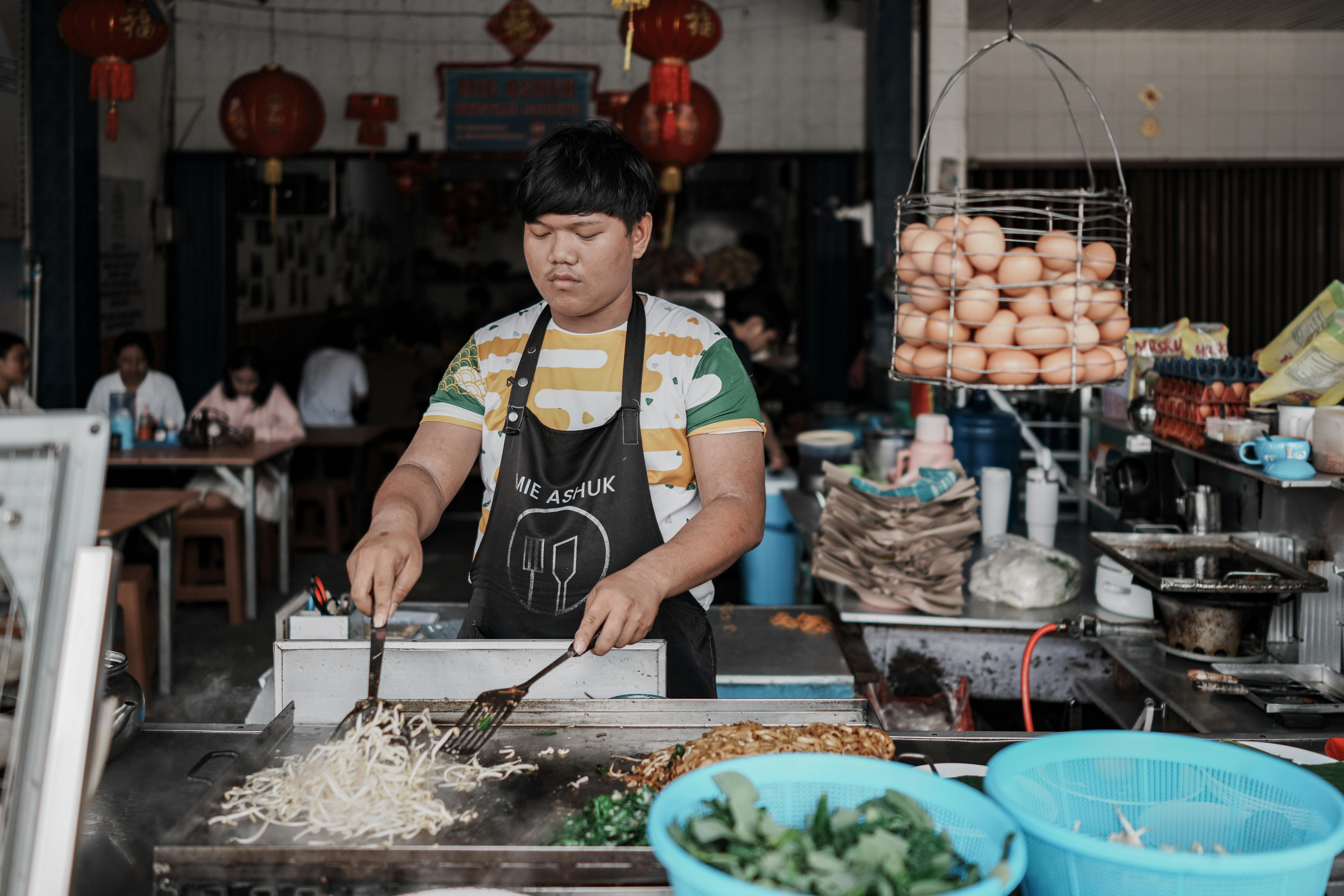 A street food vendor prepares noodles at an open-air market in Singkawang, Indonesia.