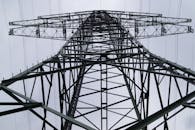 特写镜头从低角度拍摄金属电塔，背景是多云的天空