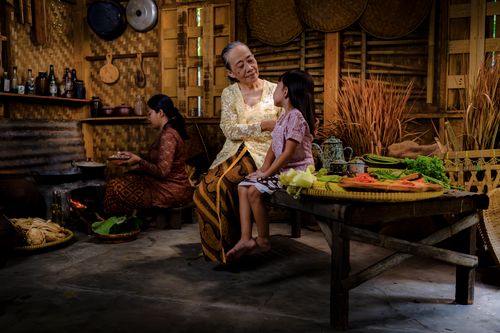 Free An intimate scene of a traditional Indonesian family gathered in a rustic kitchen setting. Stock Photo