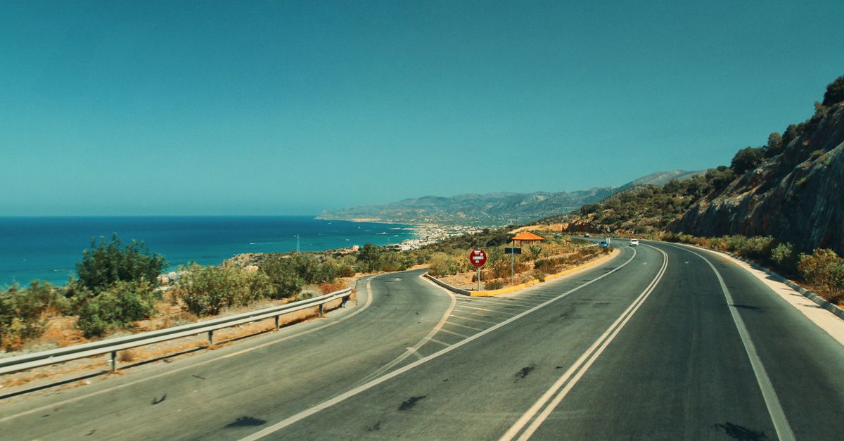 A winding road along the coast with a stunning ocean view under clear blue skies.