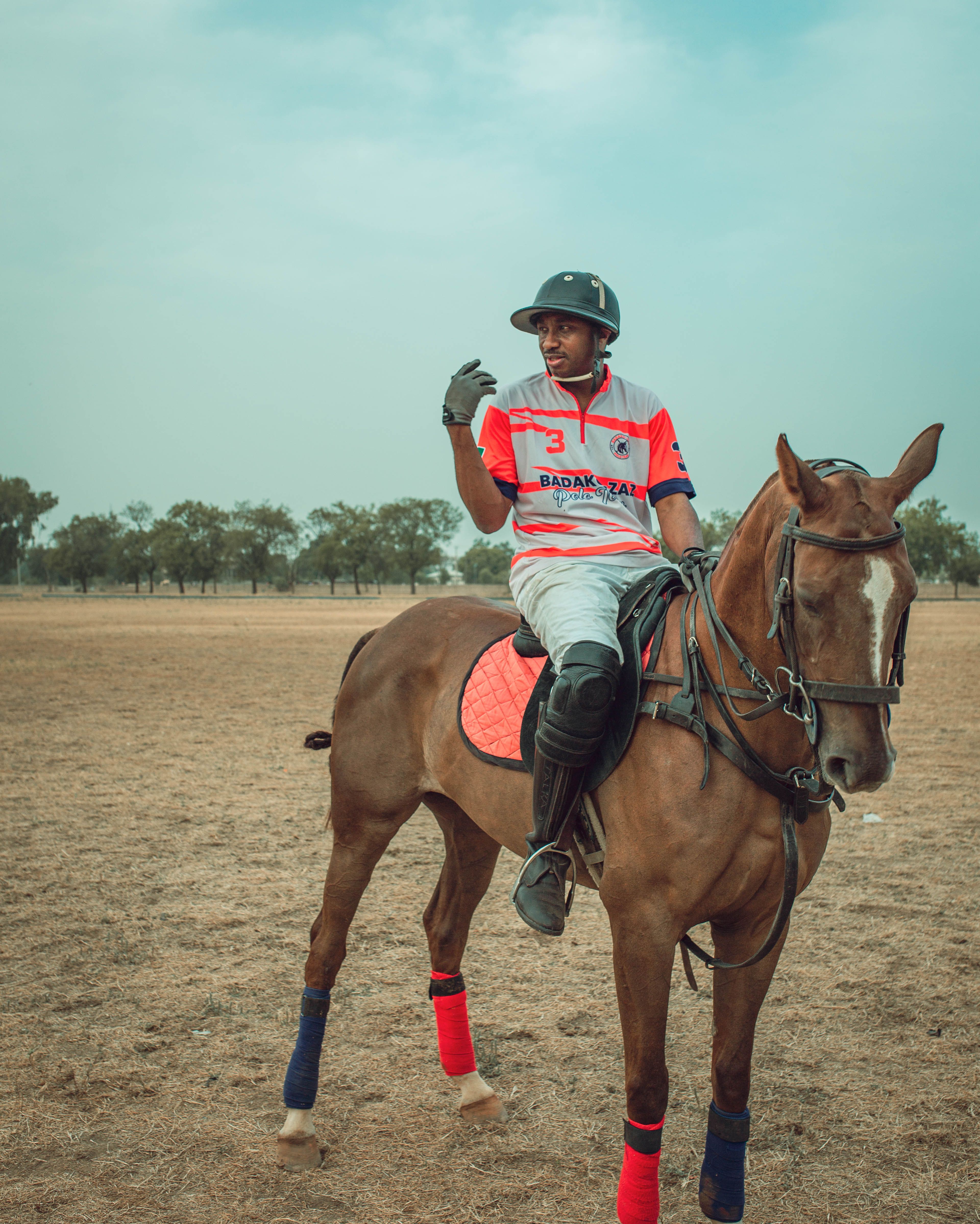 A polo player sits atop a horse in a vast field in Zaria, Nigeria, showcasing skill and tradition.