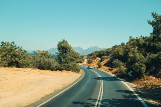 A serene drive along a winding road with mountains and lush vegetation in the background.