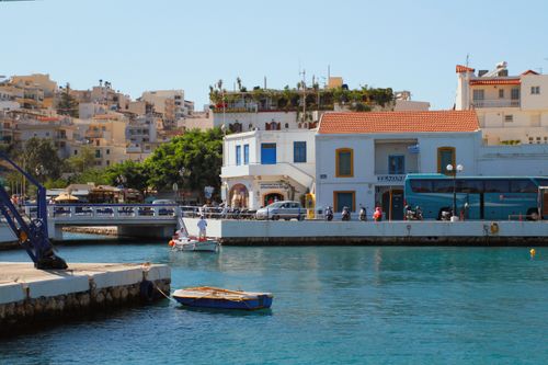 Free Vibrant waterfront scene in Agios Nikolaos, Crete, featuring a colorful boat and Mediterranean architecture. Stock Photo