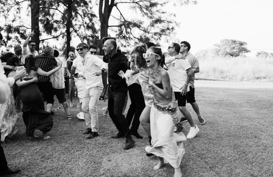 A group of adults enjoying a lively outdoor gathering, captured in black and white.