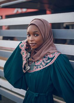 Beautiful woman with a headscarf posing in a traditional embroidered dress outdoors.