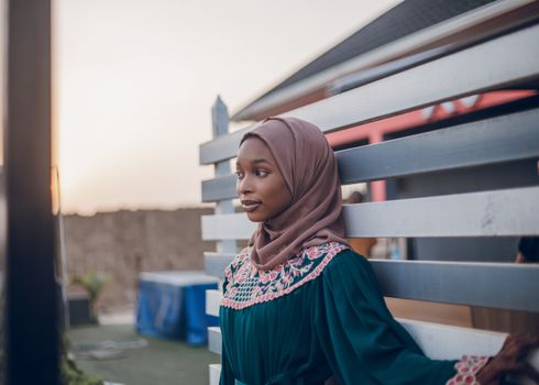 Young woman in a hijab outdoors at sunset, exuding calm and peaceful vibes.