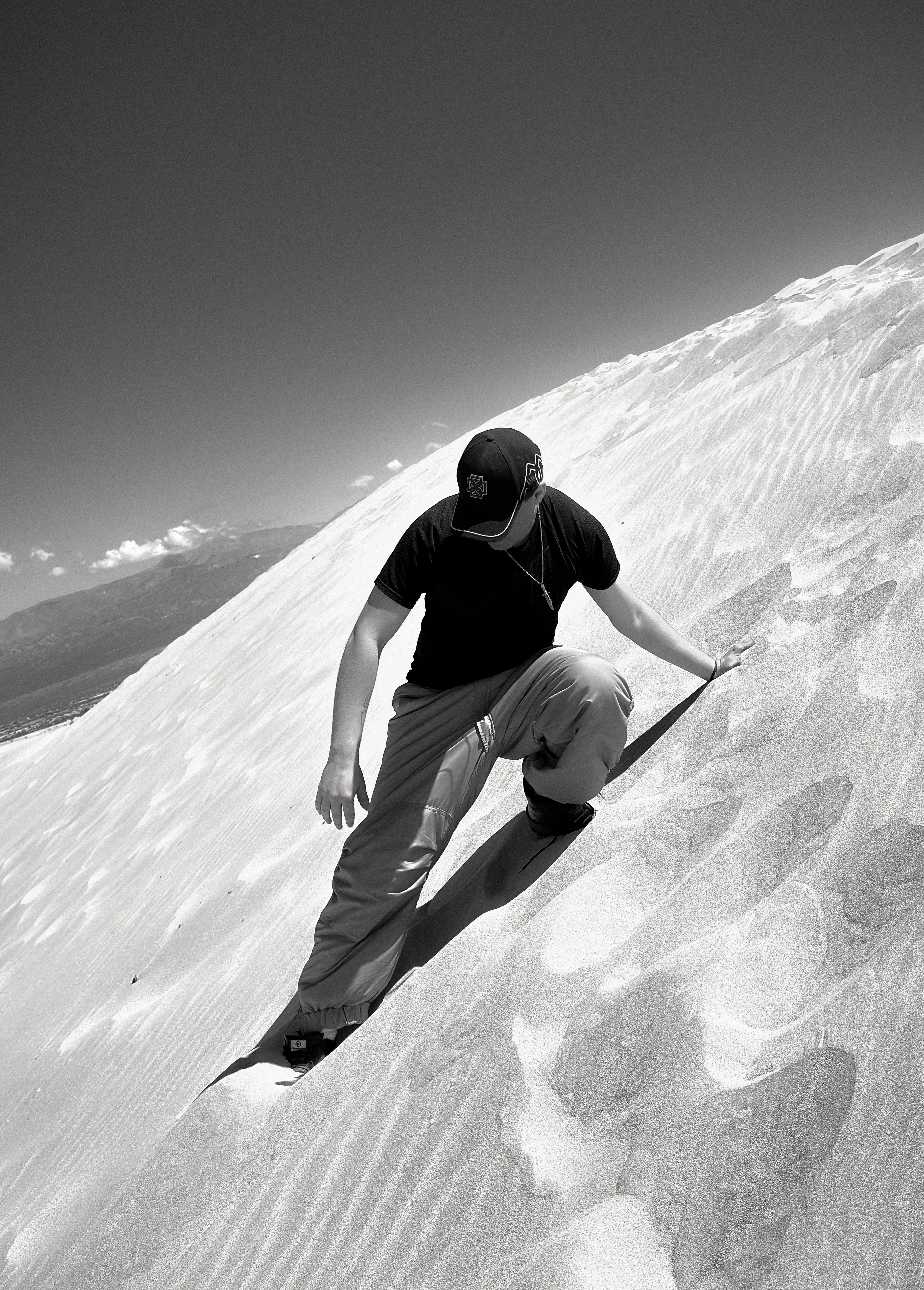 Dramatic black and white photo of a person on the sand dunes of Catamarca, Argentina.