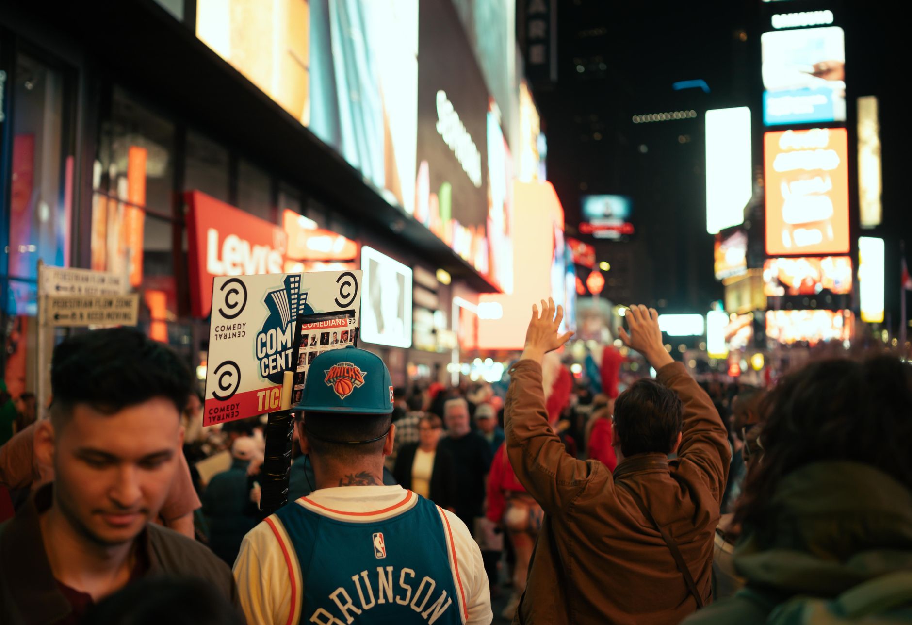 Dynamic night scene in Times Square, NYC with vibrant crowd and iconic neon lights.