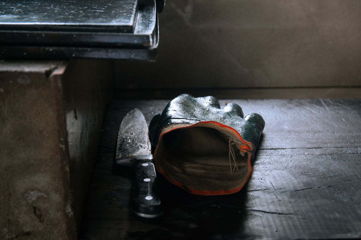 Safely handling a knife before recycling or disposal Industrial work glove resting next to a knife on a workbench