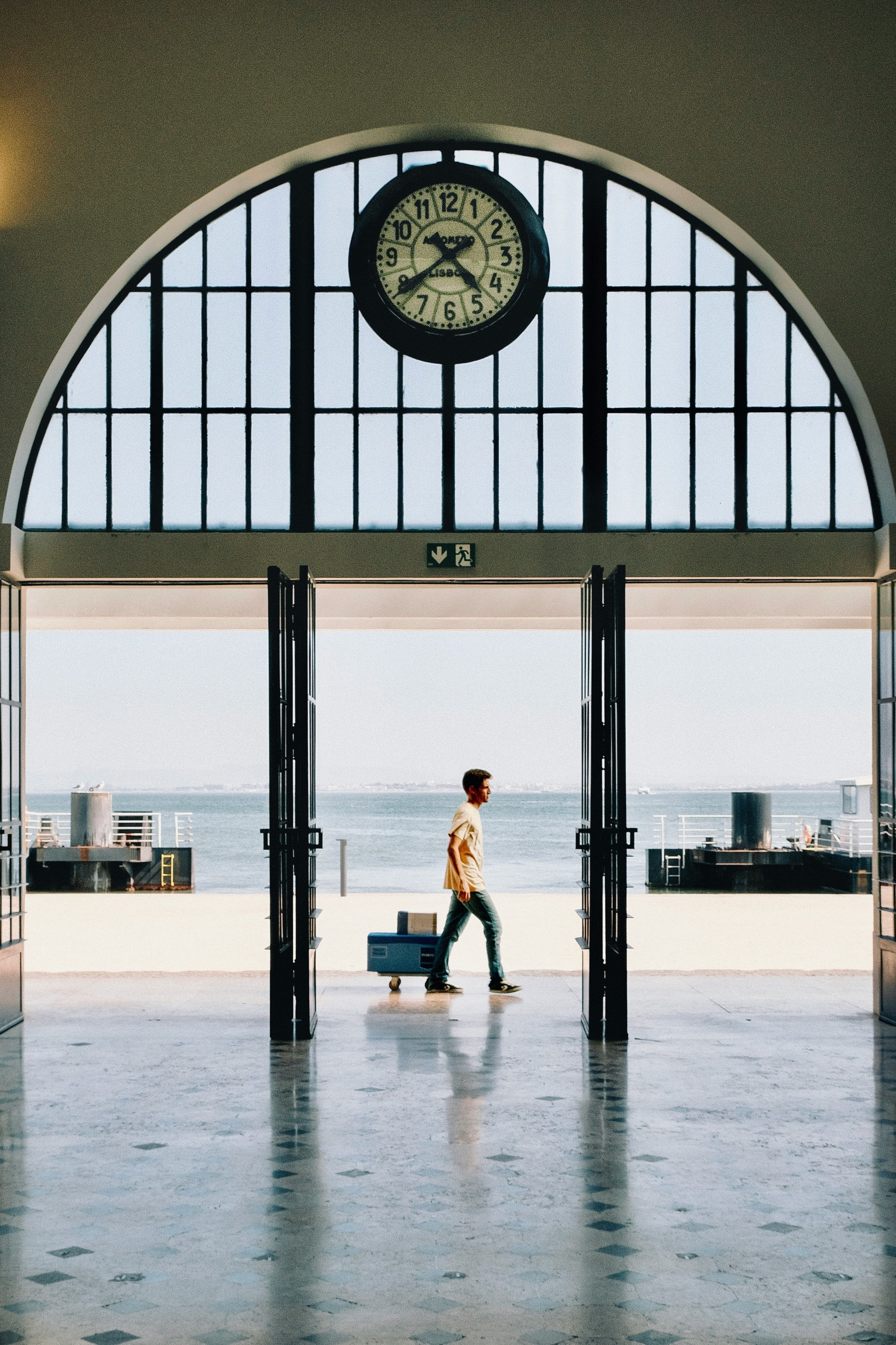 A person strides through Lisbon's iconic Terreiro do Paço station, with Tagus River visible outside.