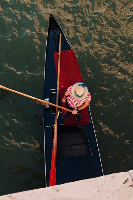 Bird's-eye view of a gondolier rowing through a canal in Venice, Italy.