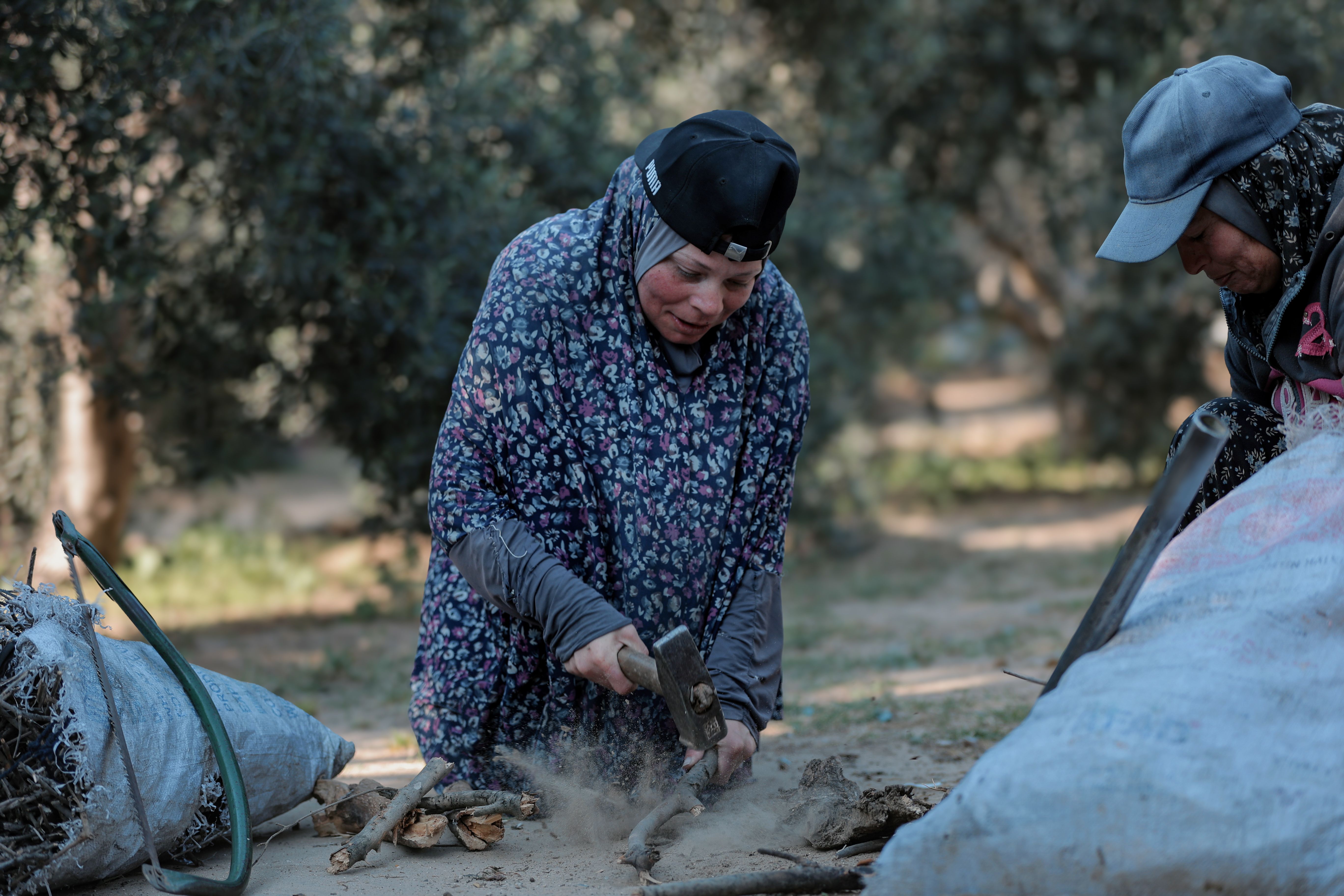 Two women engaged in manual agricultural labour outdoors in a rural setting