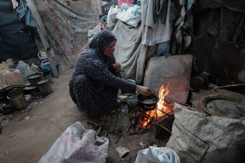 Free A woman cooks on an open flame in a rustic, makeshift environment. Stock Photo