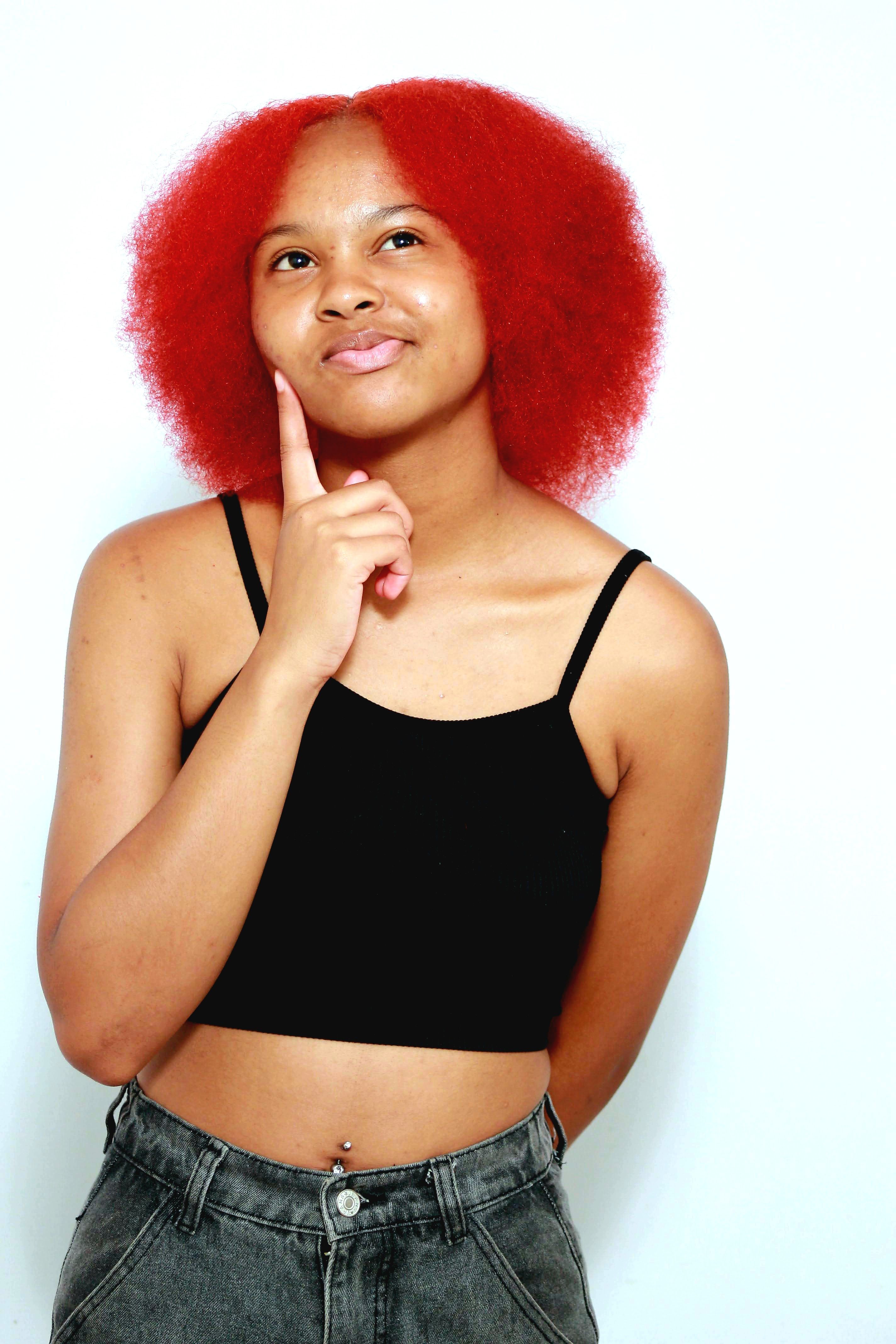Thoughtful young woman with striking red hair wearing a black top, pondering an idea.
