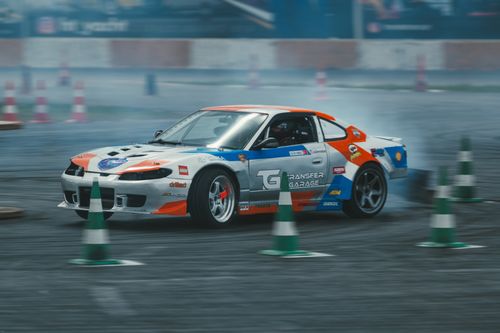 Free Action-packed scene of a customized car drifting around cones on a race track. Stock Photo