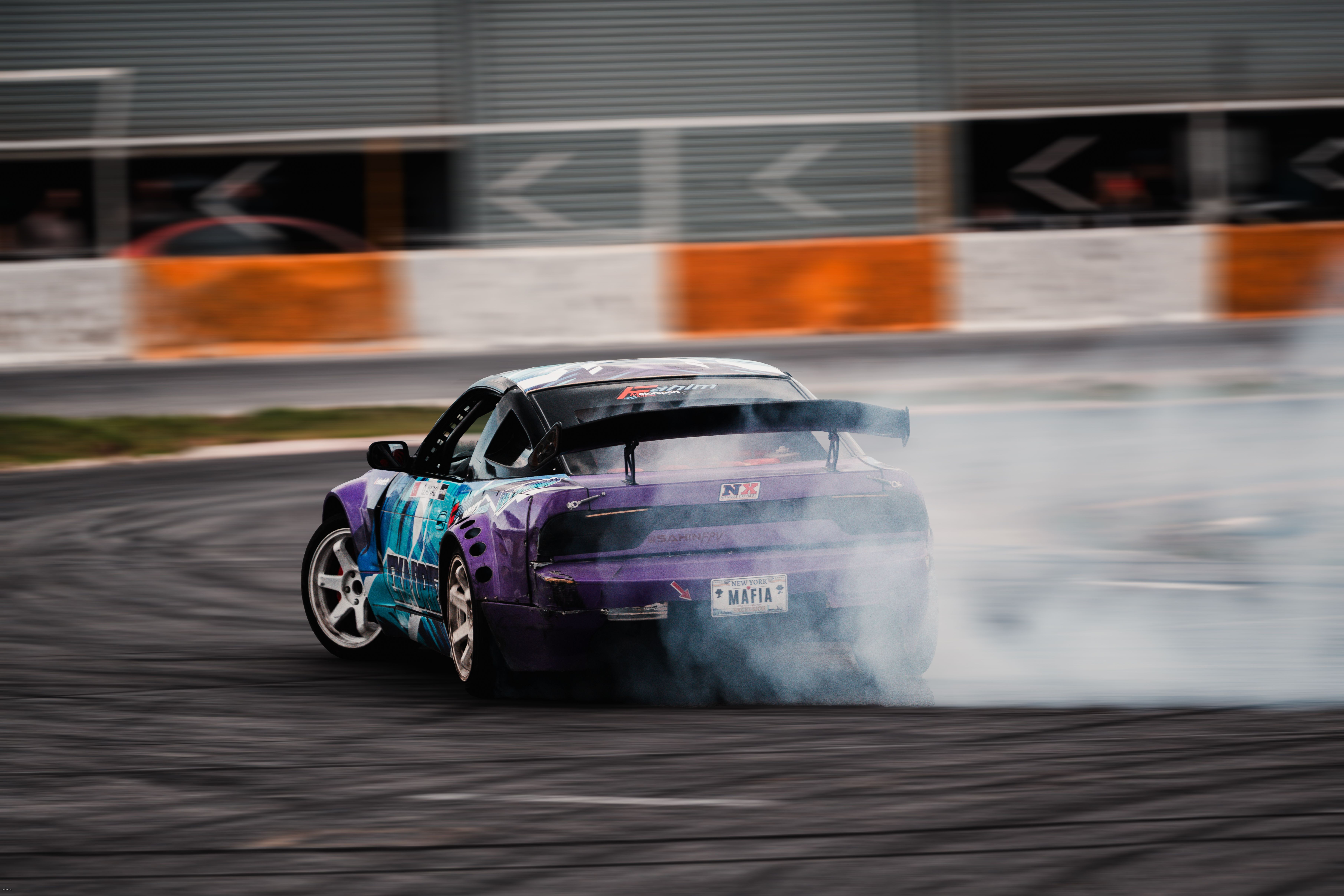 Dynamic shot of a purple sports car drifting on a race track with smoke trails.