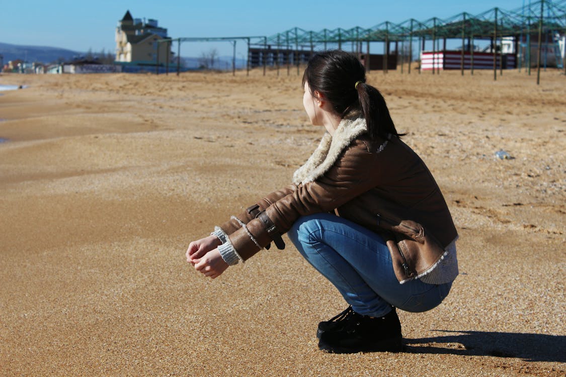 無料 茶色の砂にしゃがむ女性 写真素材