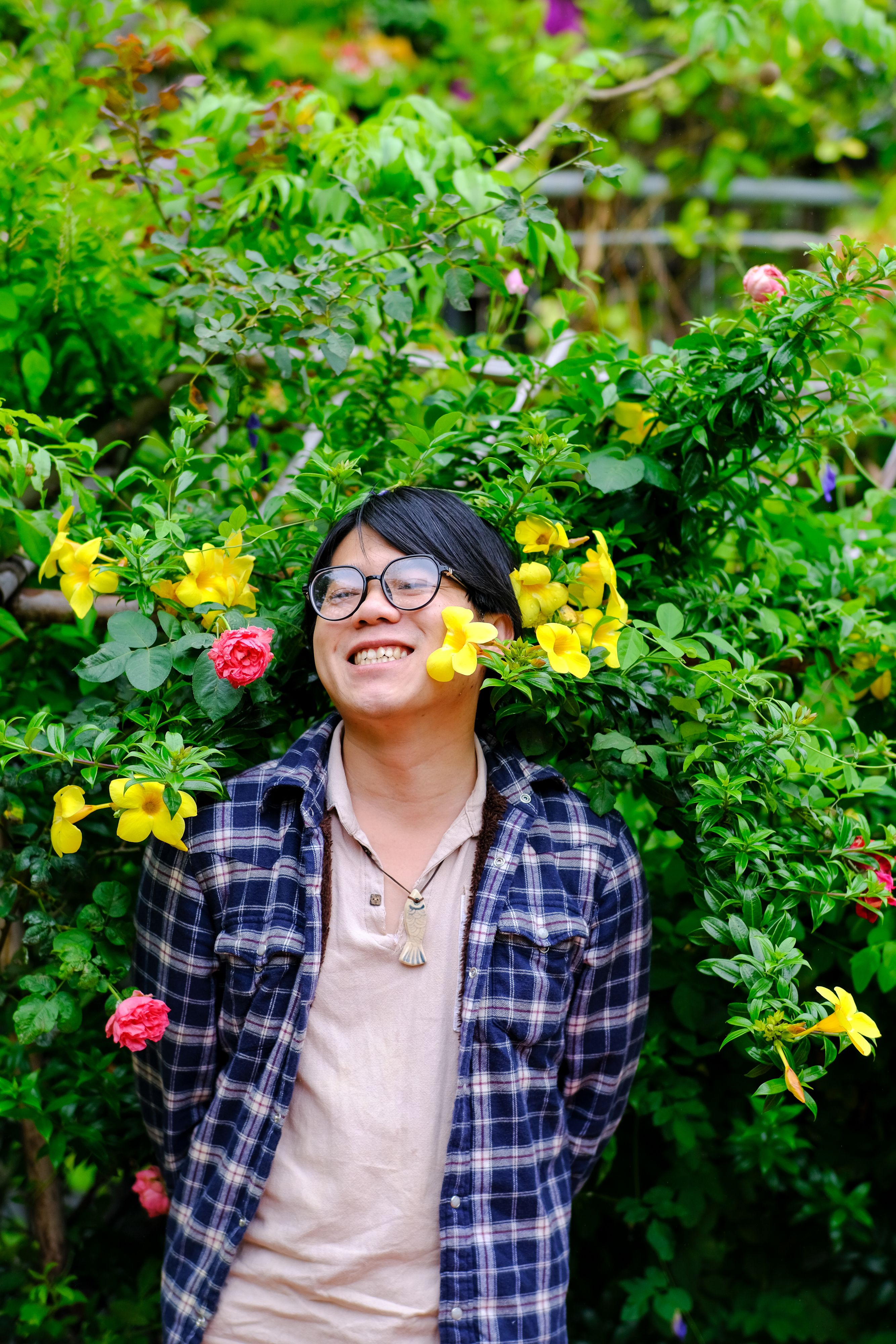 Happy person in Hue, Vietnam surrounded by vibrant flowers and greenery.
