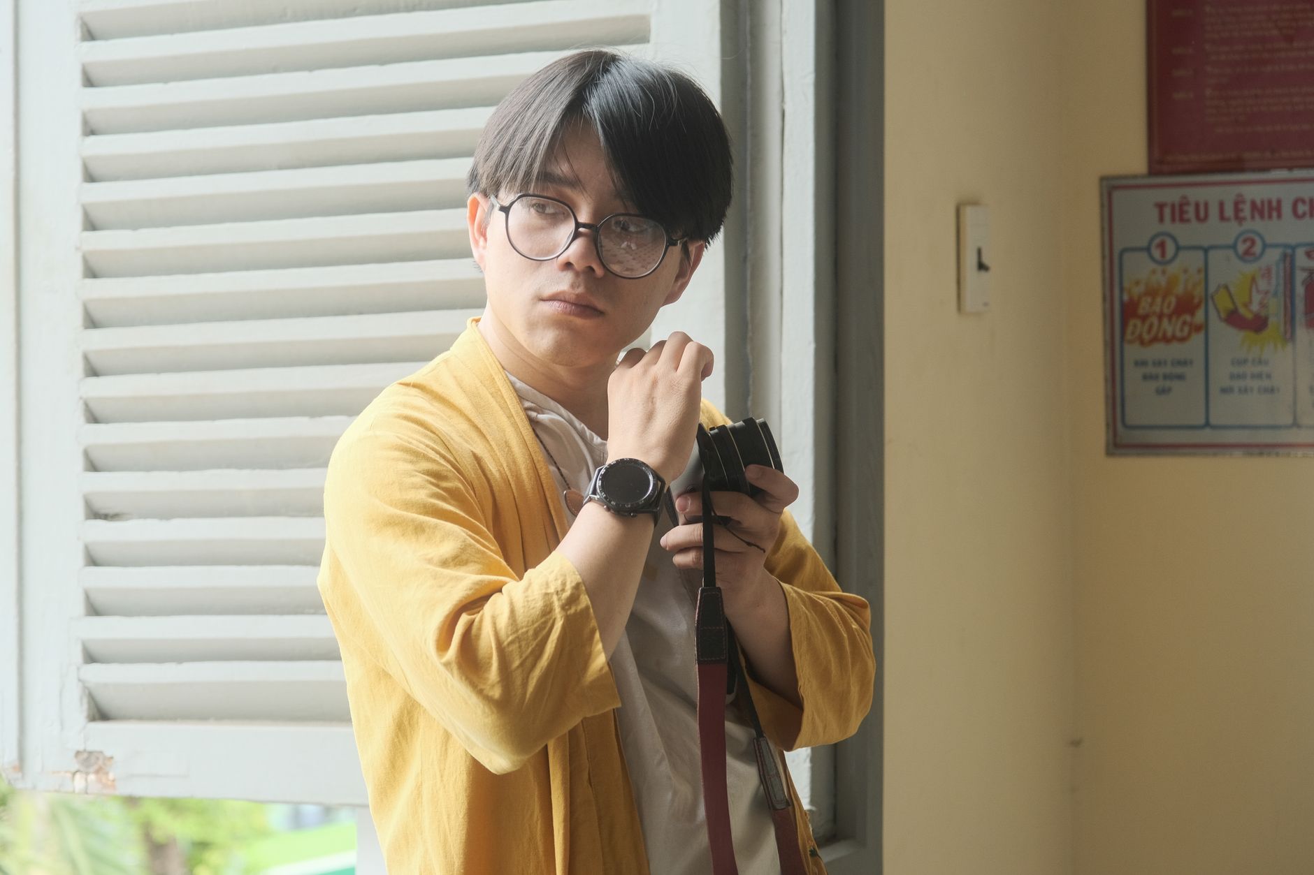 A thoughtful man with glasses in a yellow coat captured in Hue, Vietnam.