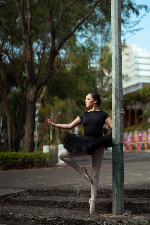 Free Elegant ballet dancer posing outdoors with a hint of urban backdrop. Stock Photo