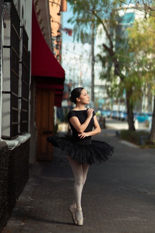 Free Ballet dancer gracefully posing in a black tutu on a city sidewalk. Stock Photo