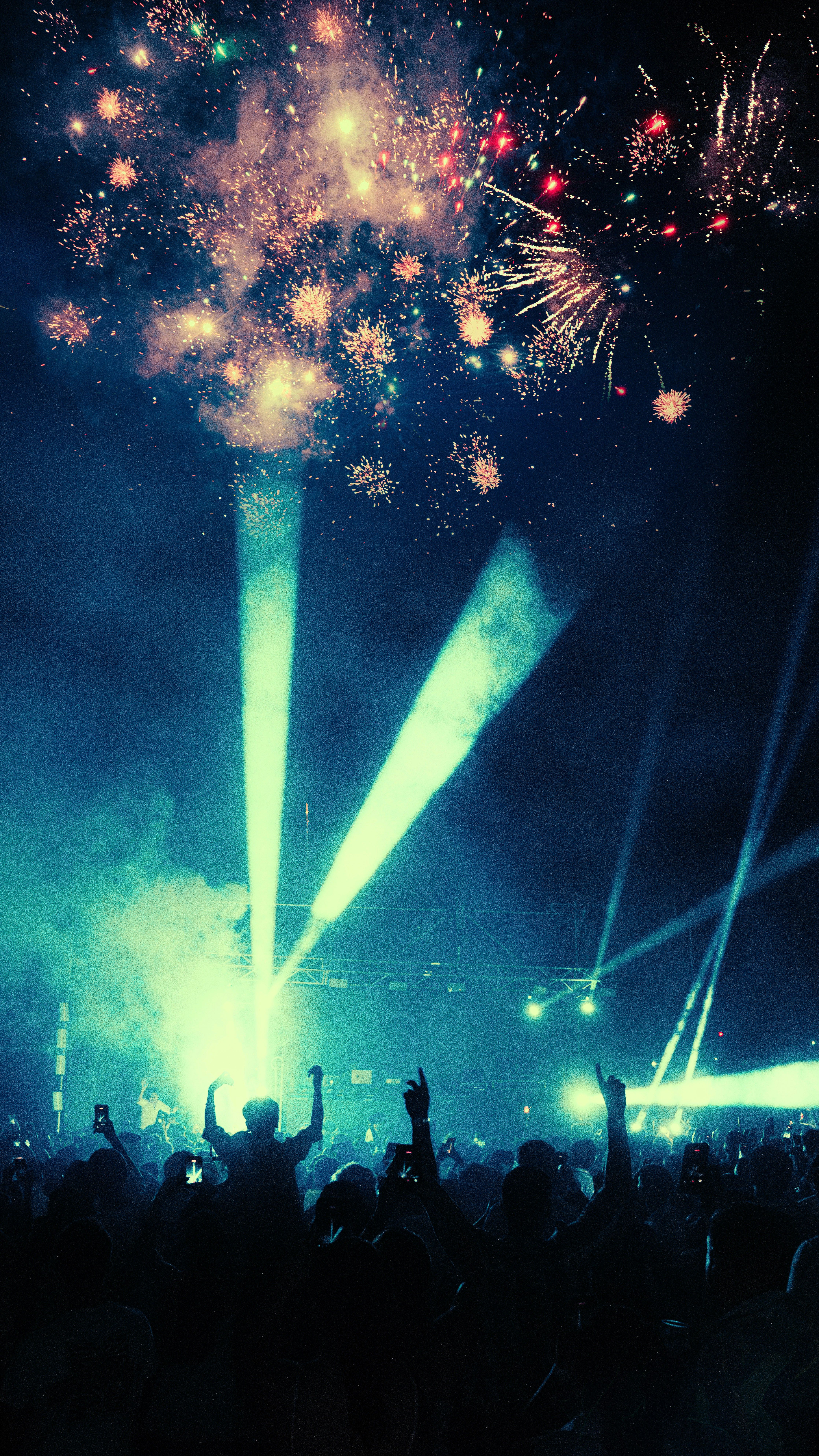 Crowd enjoying vibrant fireworks and laser show at night festival.