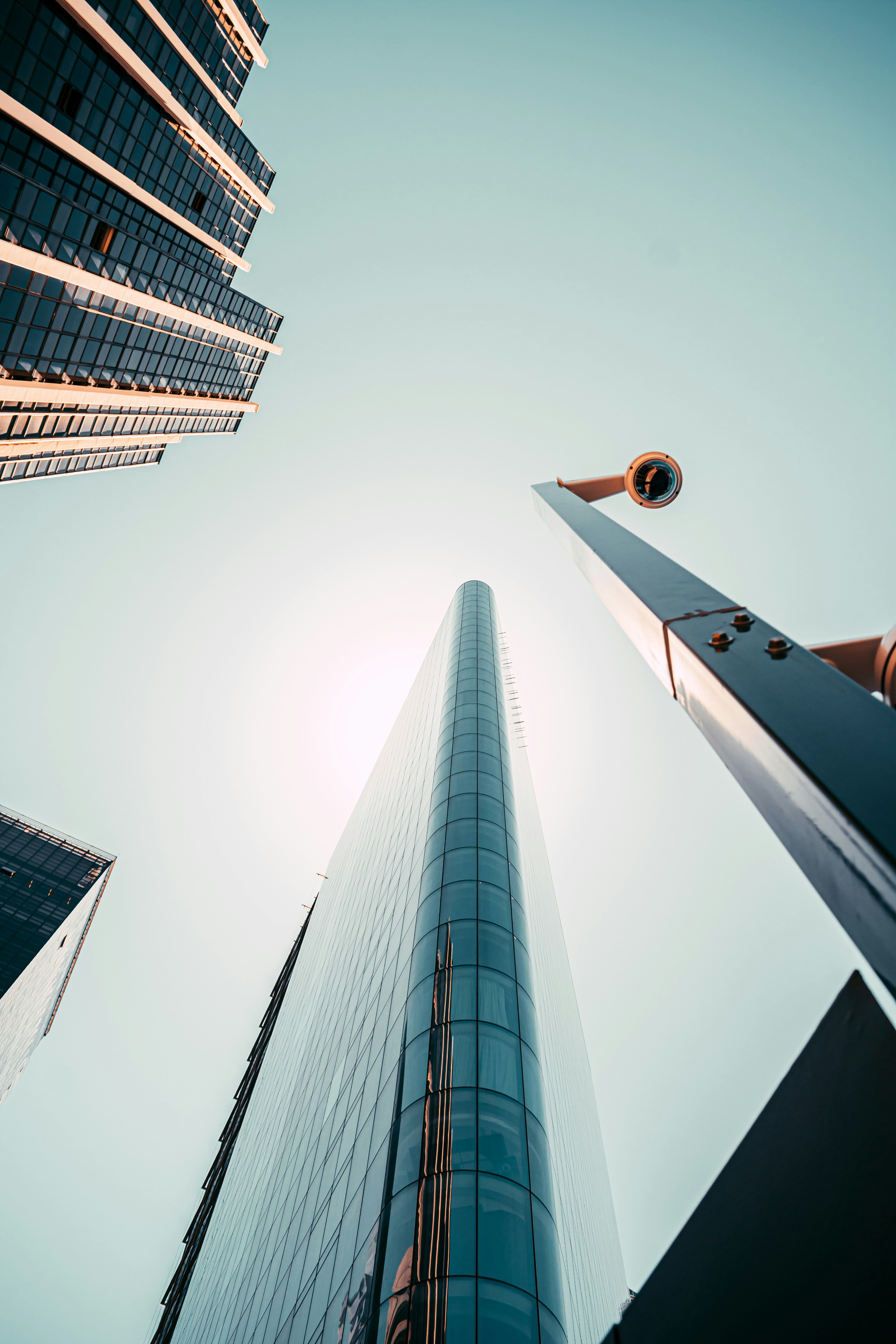 Low-angle view of sleek skyscrapers and lamp post against clear blue sky, urban architecture.