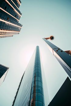 Low-angle view of sleek skyscrapers and lamp post against clear blue sky, urban architecture.