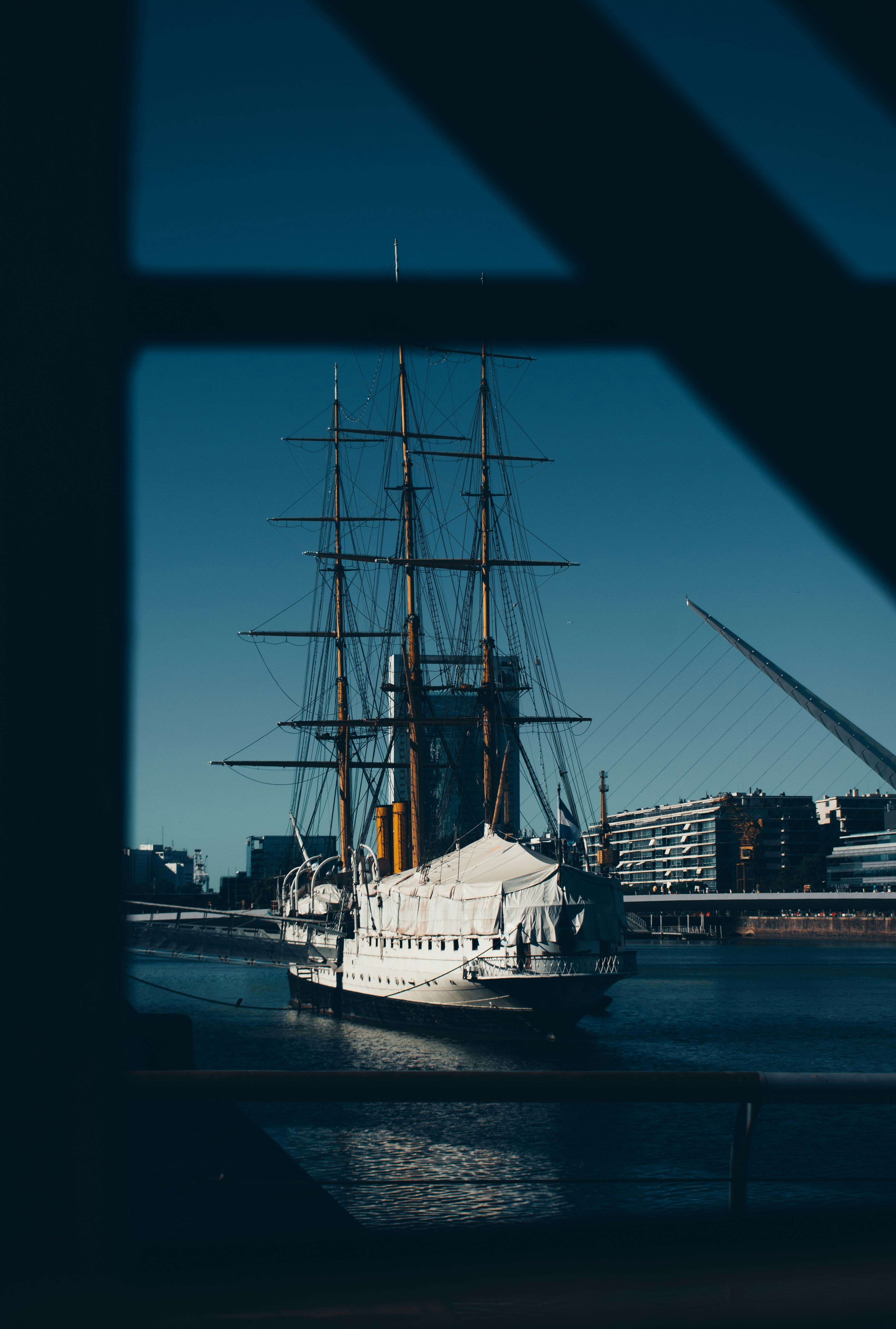 A classic sailing ship anchored by the waterfront in Buenos Aires, Argentina, framed by a window.