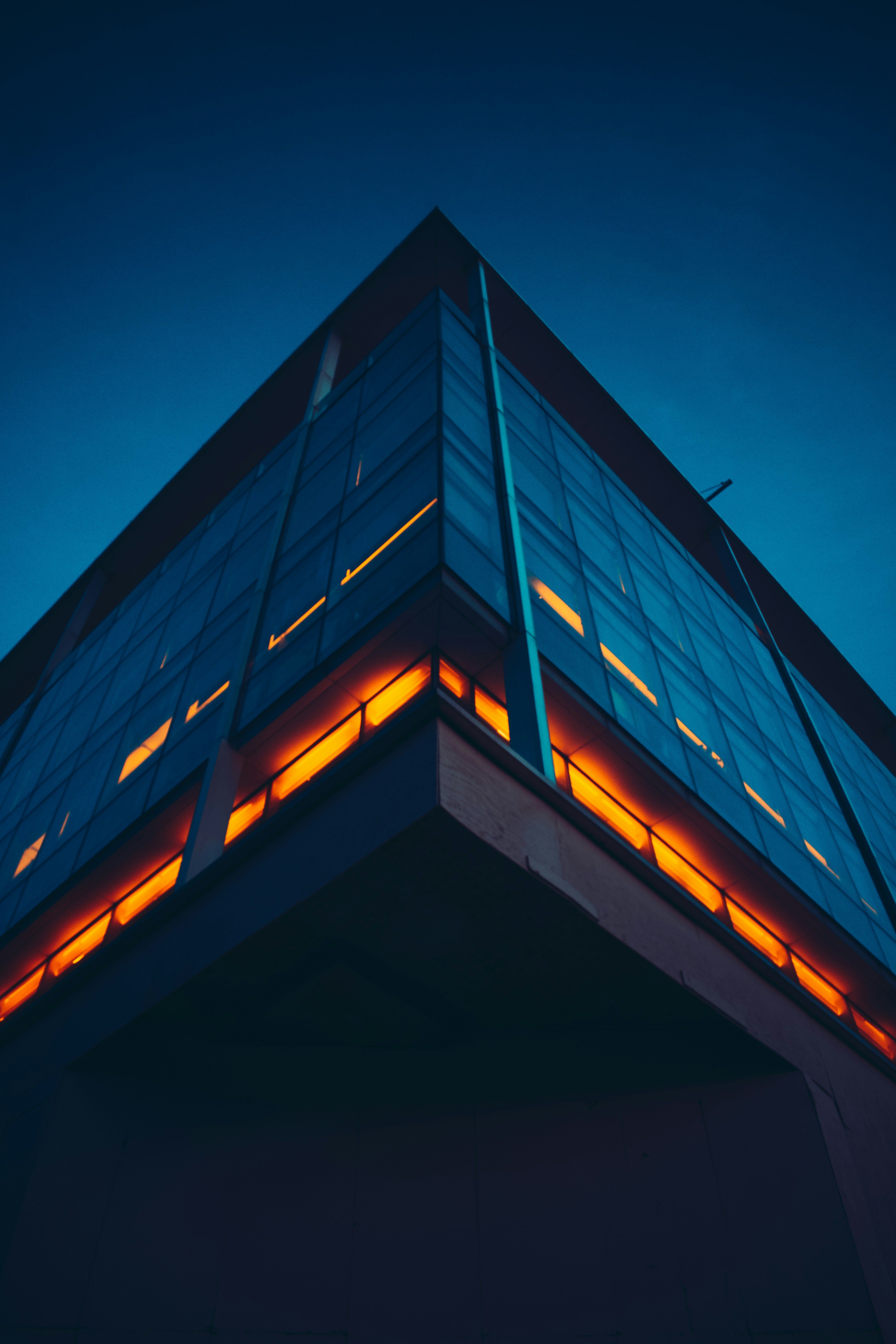 Stylish modern building facade with illuminated windows under evening sky.