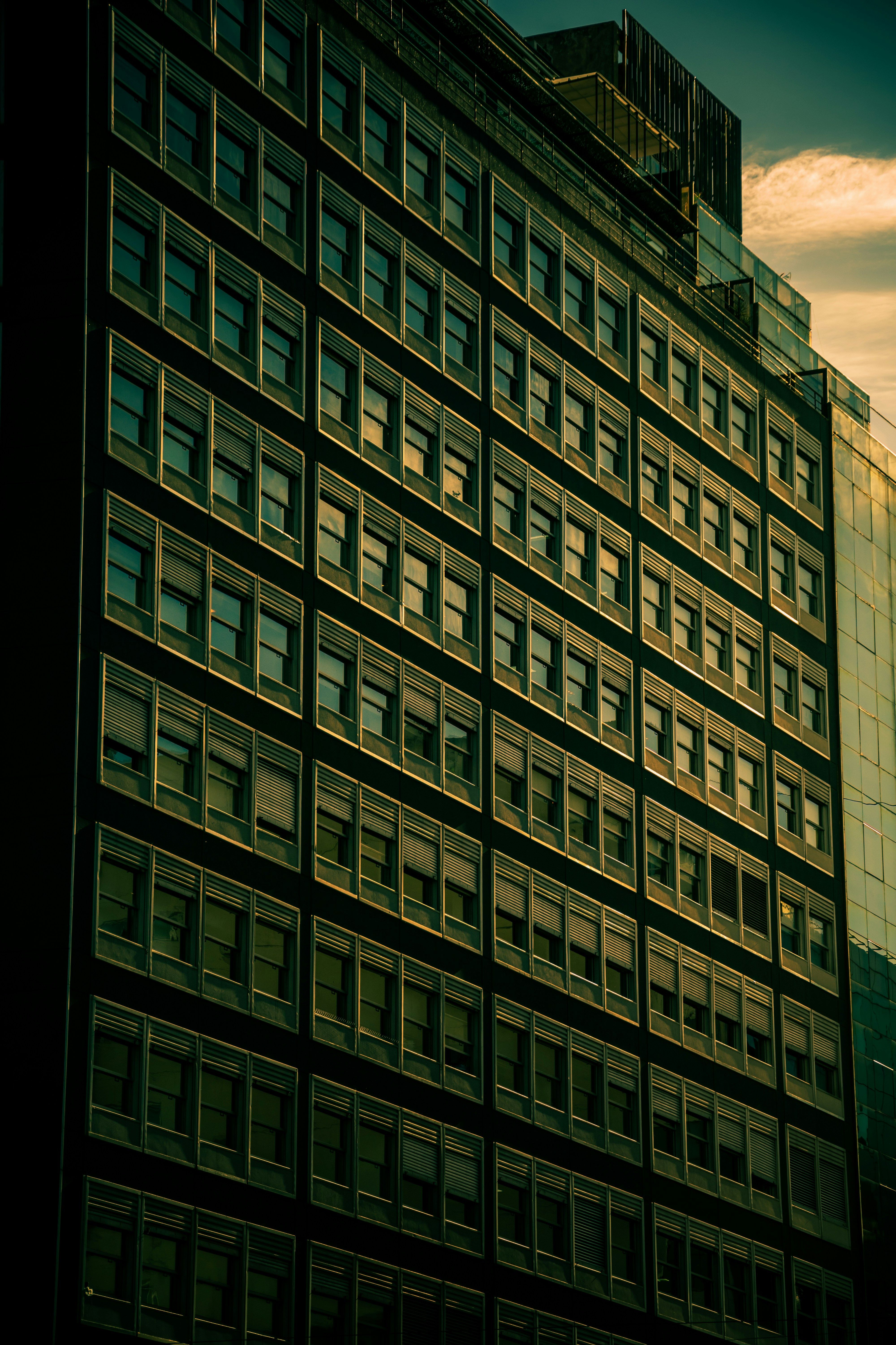 Sunlit urban high-rise building with reflective glass windows and geometric pattern.